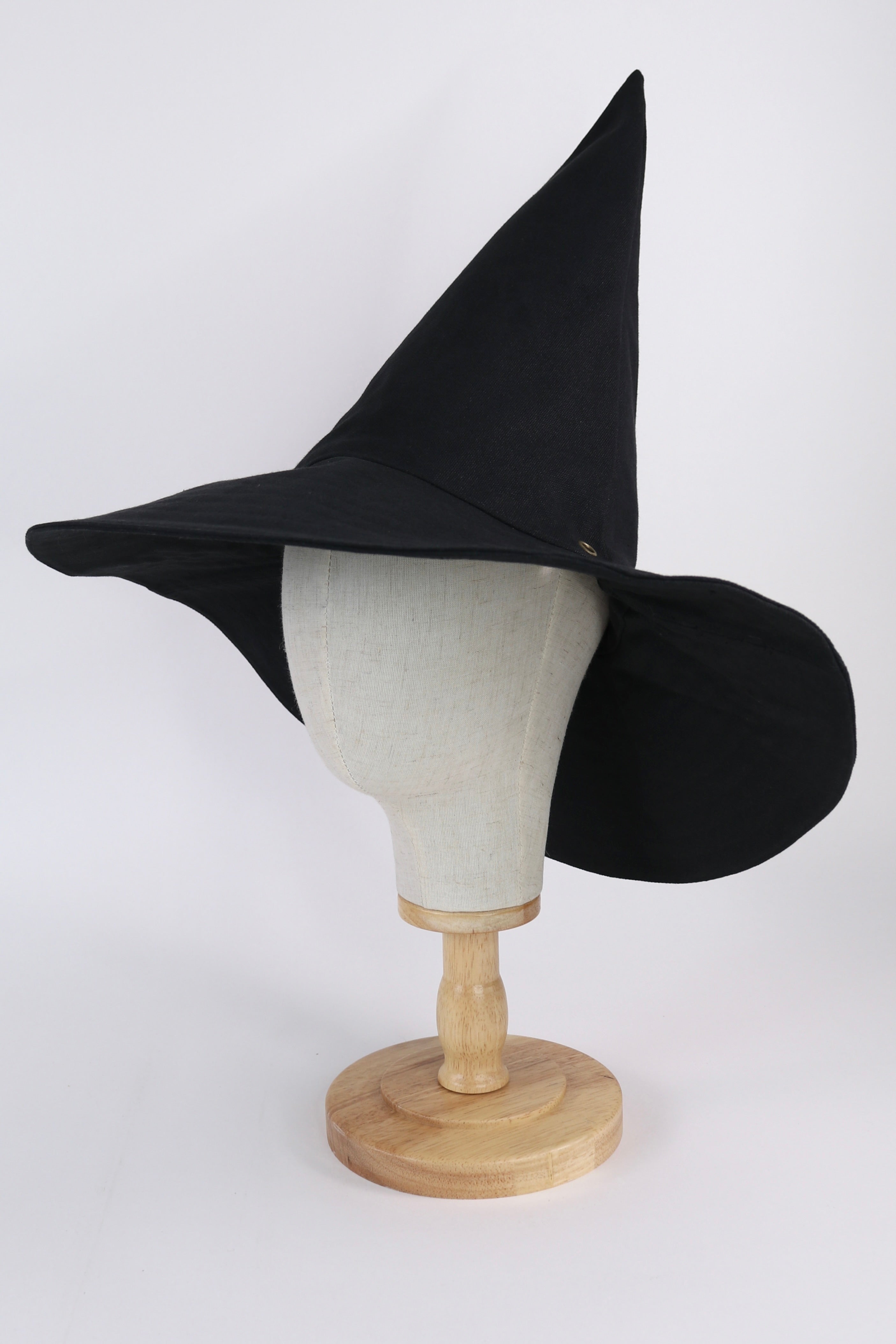 Black witch hat on a wooden mannequin head against a white background