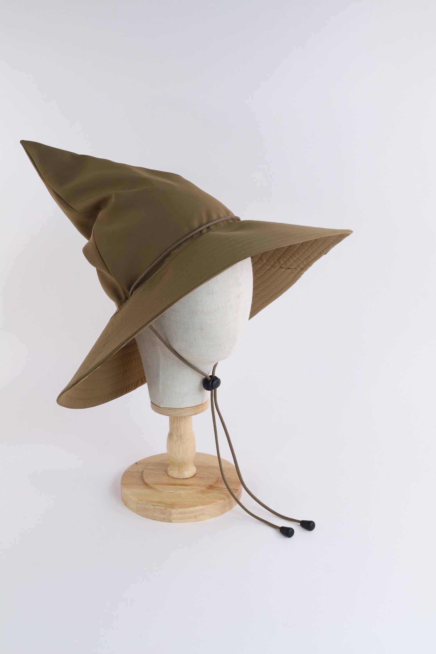 Brown Wizard Bucket hat with brown adjustable chin strap on a creamy white cotton head mannequin against a white background. 