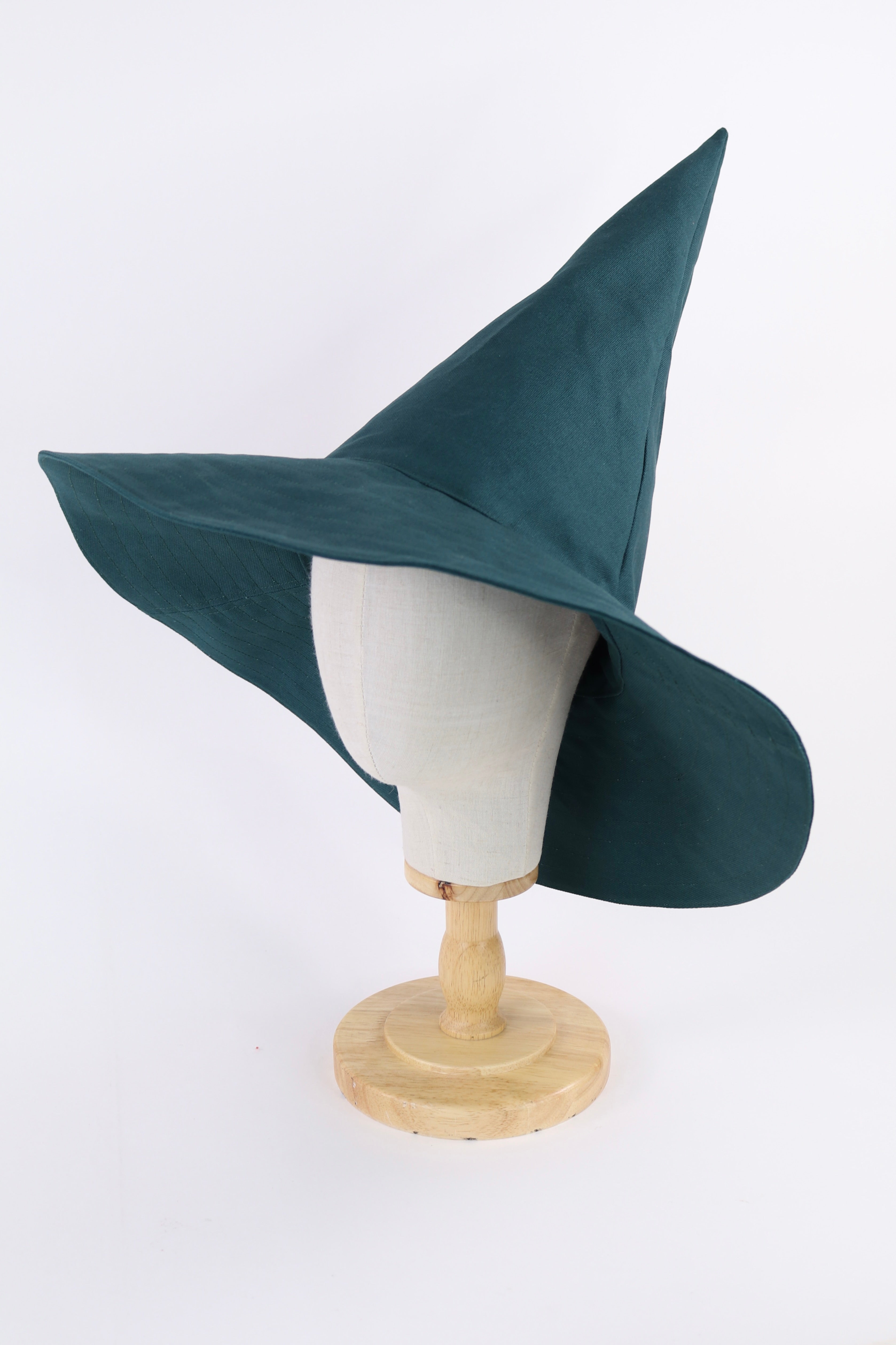 Teal witch hat on a mannequin head against a white background