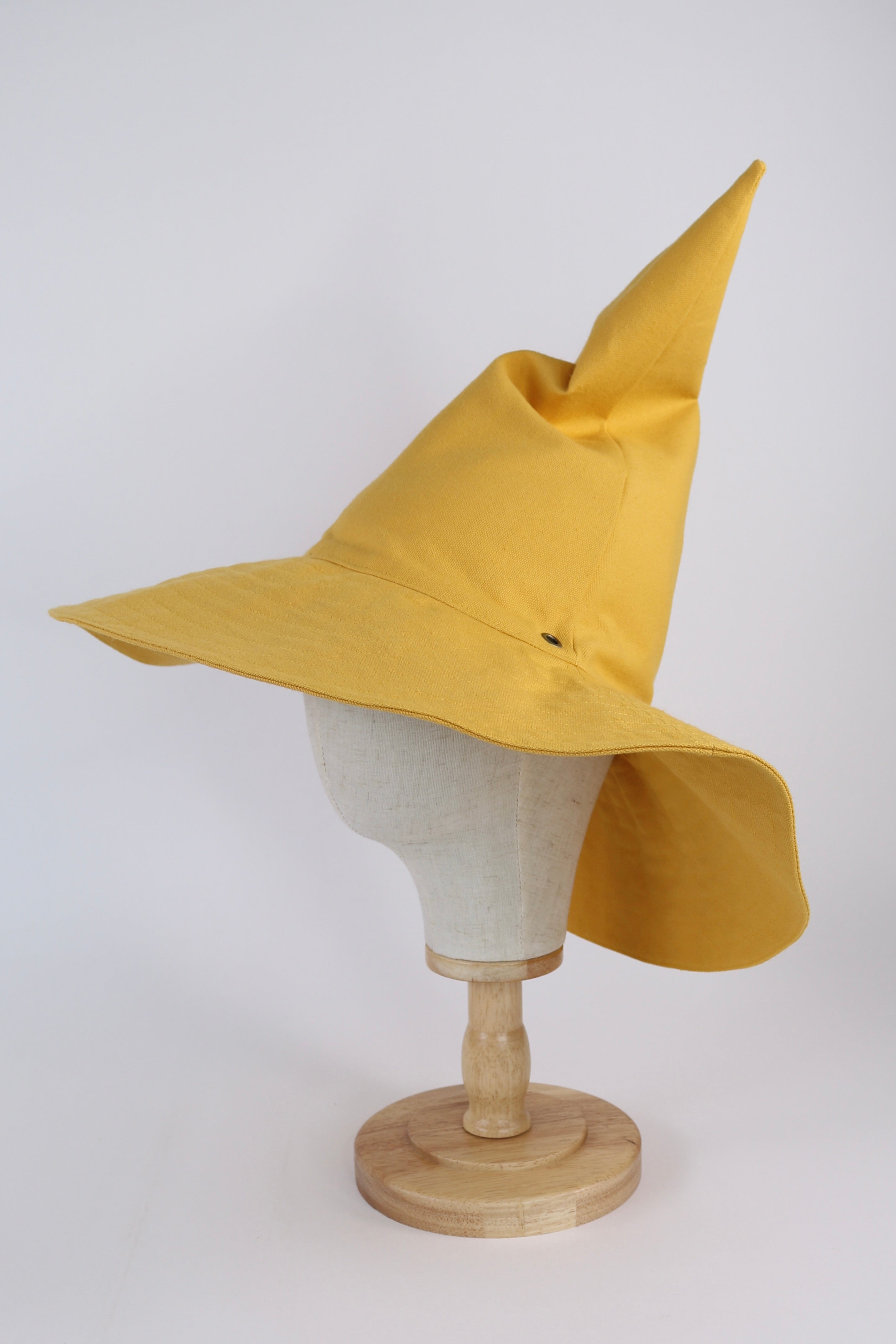 Yellow witch hat on a mannequin head against a white background