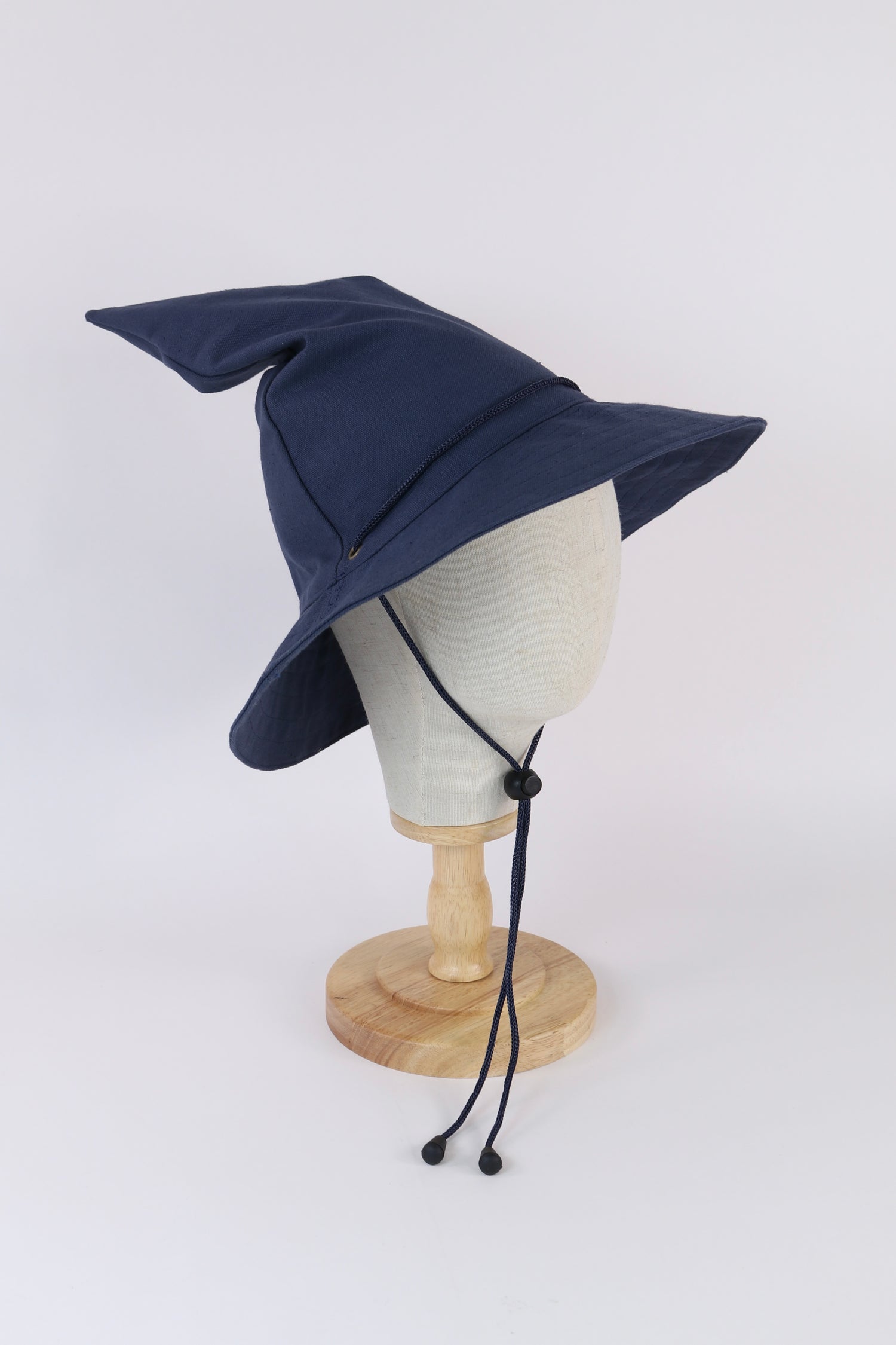 Navy blue canvas Sunbound wizard bucket hat with matching strap, side view on muslin head mannequin with crown tilted back