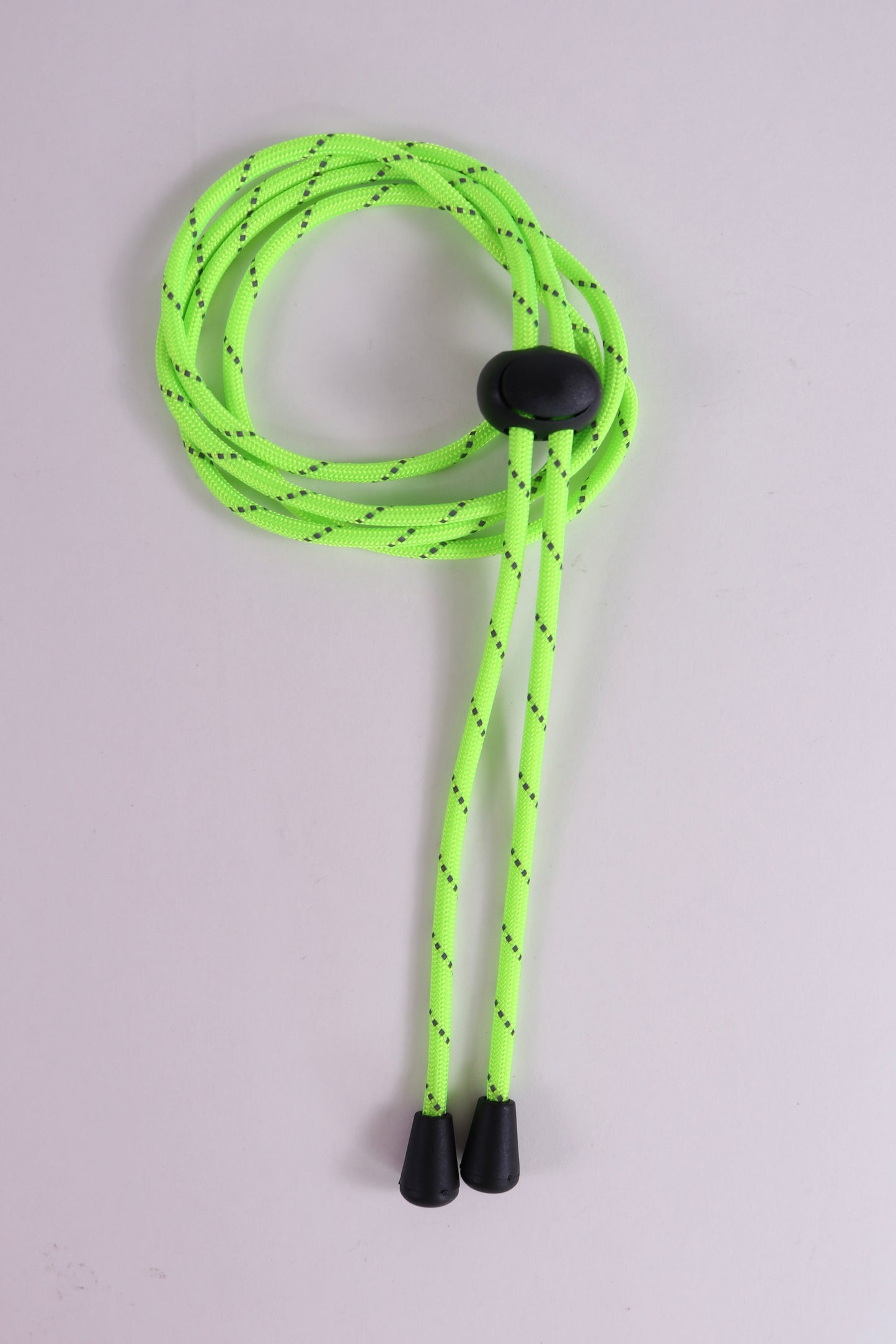 Neon green shoelace with black tips on a light gray background